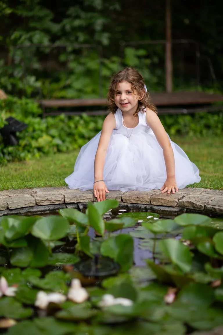Une petite fille en robe blanche près d'un bassin