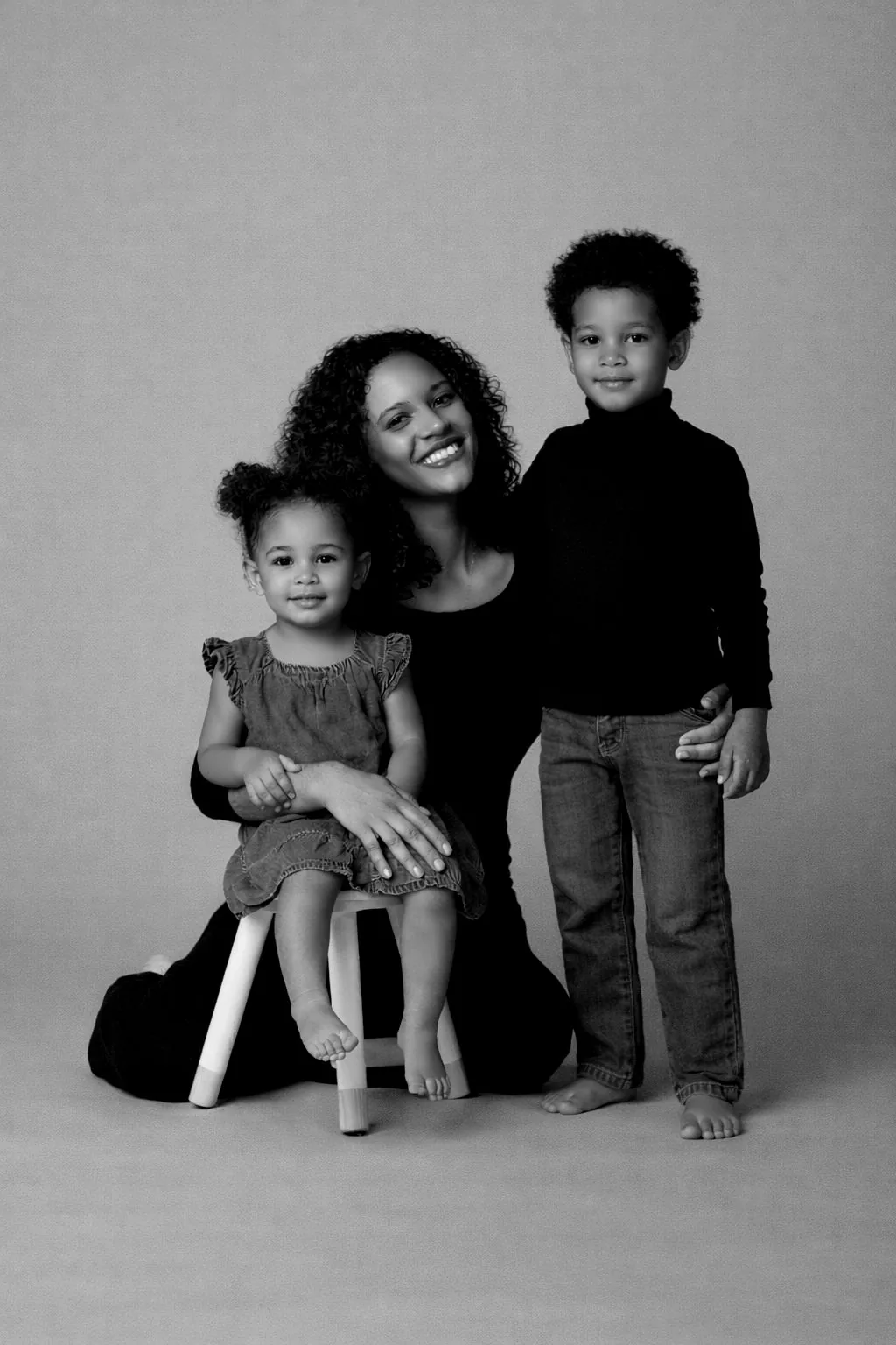 Une maman et ses deux enfants au studio, fond rose poudré