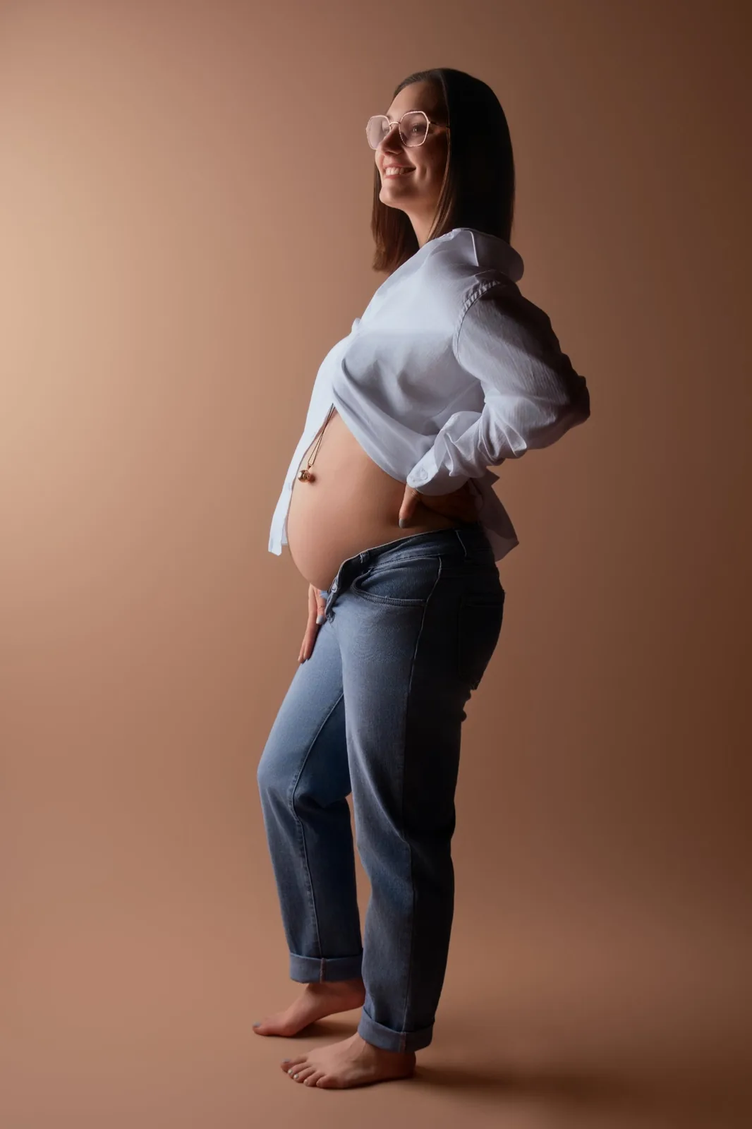 Future maman souriante en chemise blanche et jean