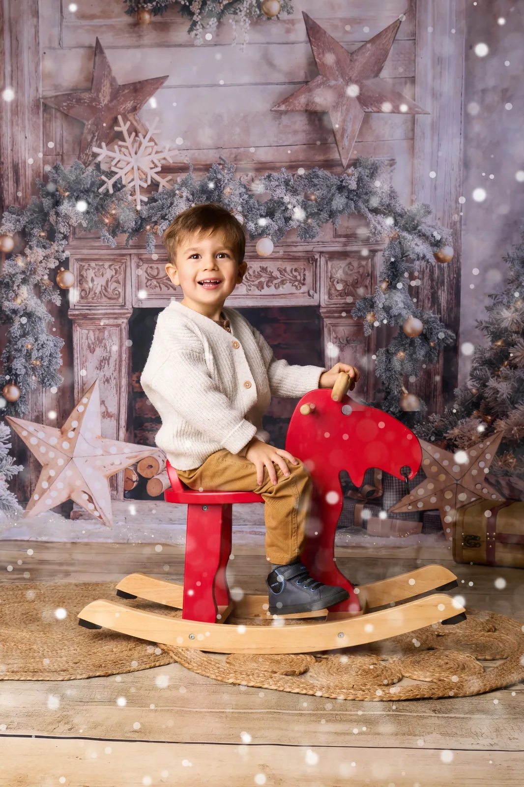 Petit garçon sur un renne à bascule, décor de Noël enneigé