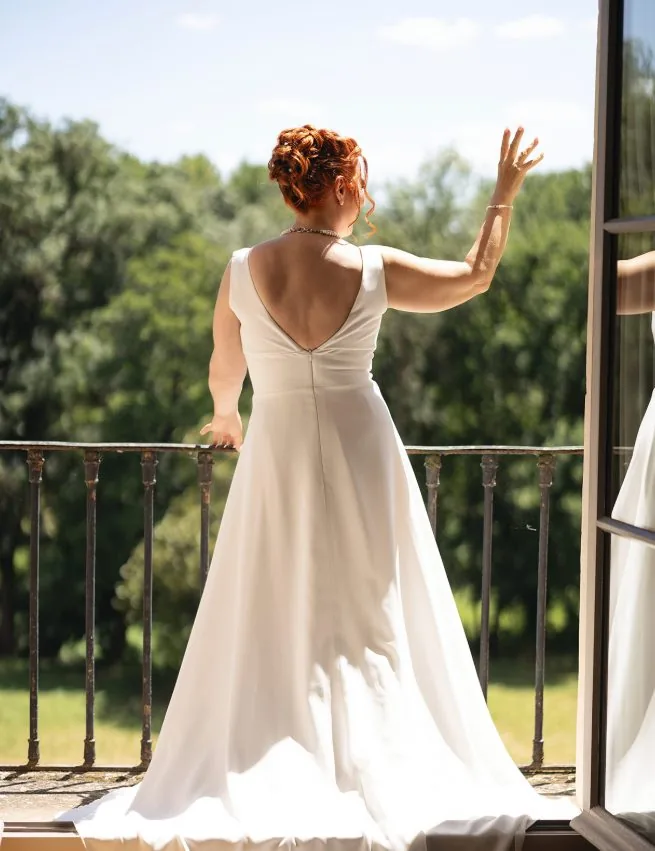 La mariée de dos sur un balcon, saluant ses invités