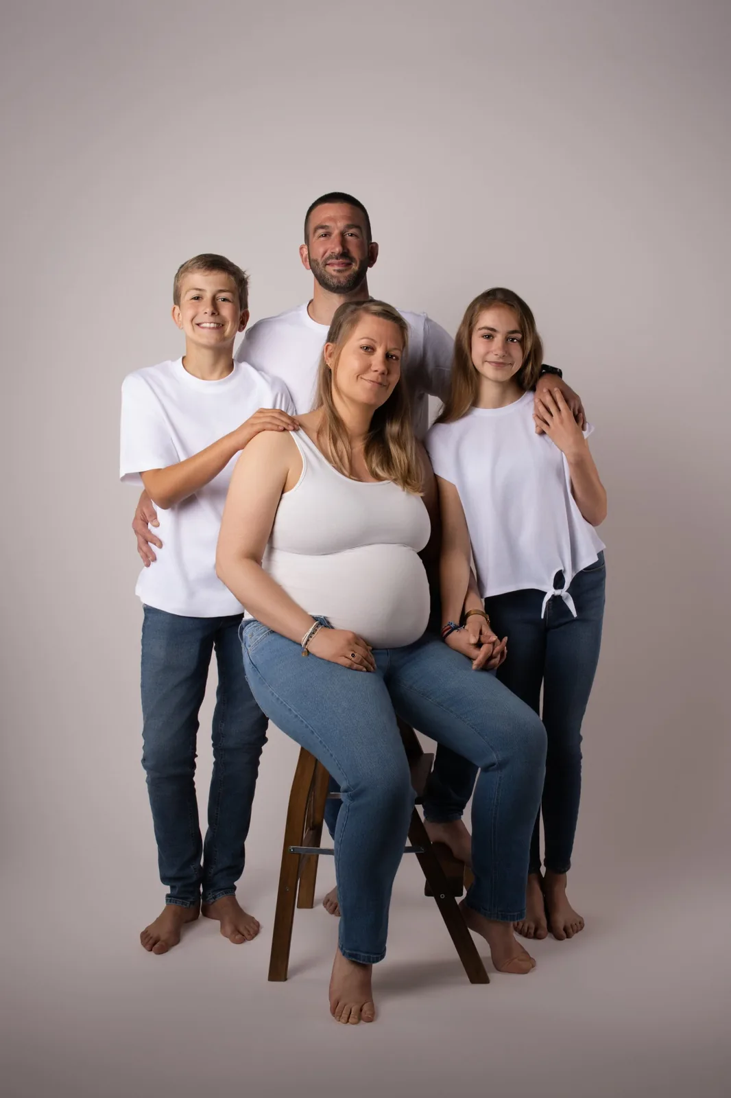 Future maman assise entourée de son conjoint et de leurs deux ados