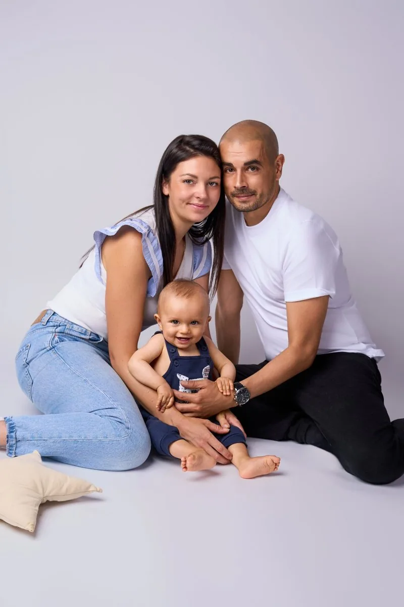 Famille assise au studio avec leur bébé souriant