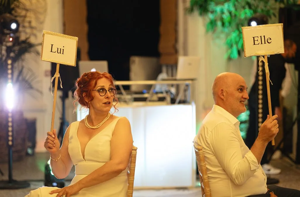 Les mariés jouent au jeu des panneaux « Lui » et « Elle » pendant la soirée