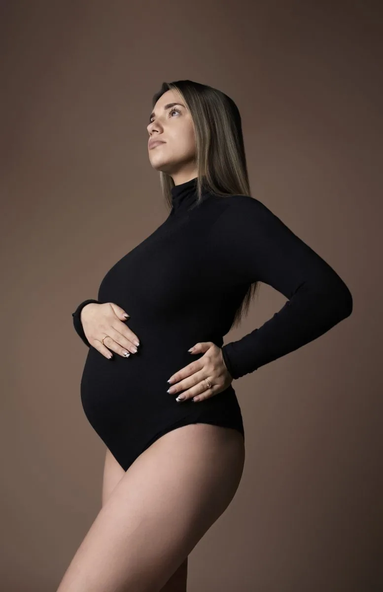 Future maman en body col roulé noir, regard vers le haut