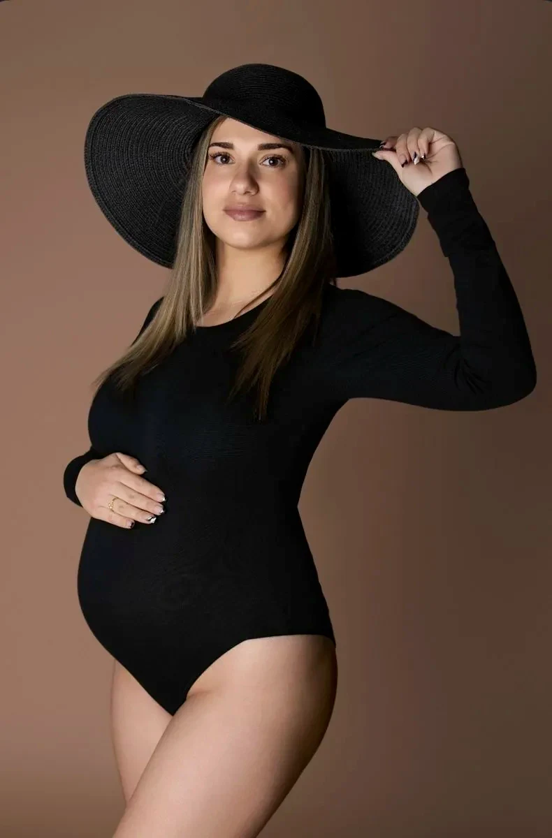 Future maman en body noir et grand chapeau